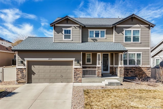 craftsman-style home featuring stone siding, a porch, driveway, and fence