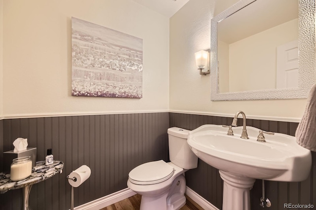 8657 Aberdeen Cir, Highlands Ranch, CO 80130 - half bath featuring wainscoting, toilet, wood finished floors, and a sink