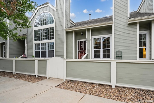 5875 W Asbury Pl, Lakewood, CO 80227 - property entrance featuring fence, a gate, a chimney, and a shingled roof