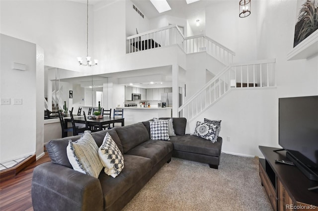 5875 W Asbury Pl, Lakewood, CO 80227 - living area featuring visible vents, stairs, a towering ceiling, a chandelier, and a skylight
