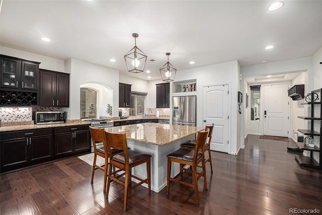 11511 E 118th Ave, Commerce City, CO 80640 - kitchen featuring stainless steel appliances, a breakfast bar, tasteful backsplash, dark wood-type flooring, and a kitchen island