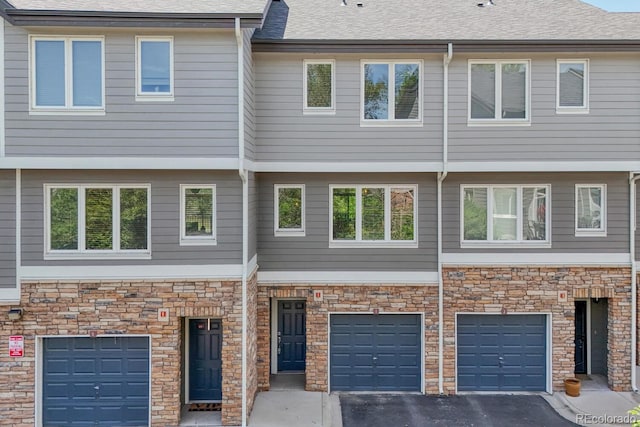 2943 W Riverwalk Cir Unit I, Littleton, CO 80123 - view of front of home featuring an attached garage, driveway, and stone siding