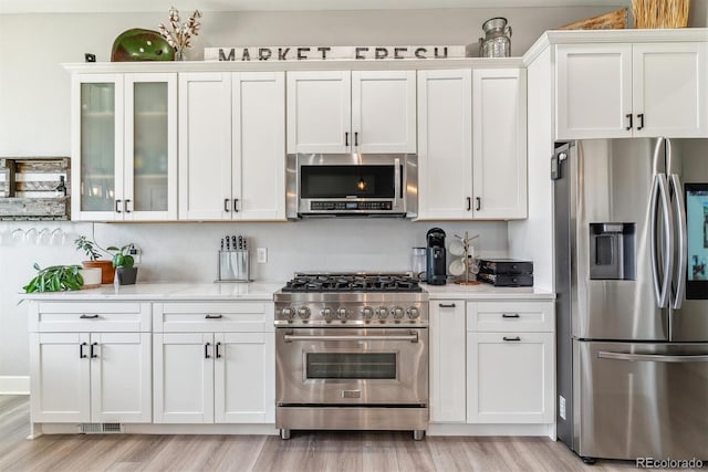 527 Antelope Dr E, Bennett, CO 80102 - kitchen featuring stainless steel appliances, light countertops, light wood finished floors, and white cabinets