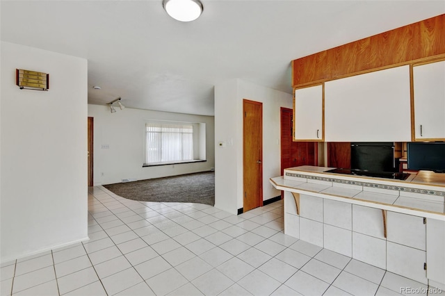 11310 W Center Ave, Lakewood, CO 80226 - kitchen with tile countertops, open floor plan, white cabinets, light tile patterned floors, and baseboards