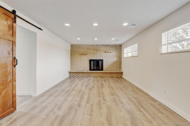 11310 W Center Ave, Lakewood, CO 80226 - unfurnished living room featuring a barn door, recessed lighting, light wood finished floors, a fireplace, and baseboards