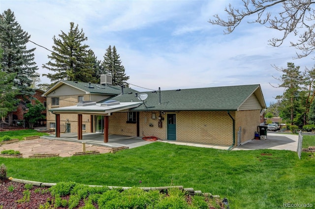 11310 W Center Ave, Lakewood, CO 80226 - rear view of property featuring a patio, brick siding, a yard, central air condition unit, and a shingled roof