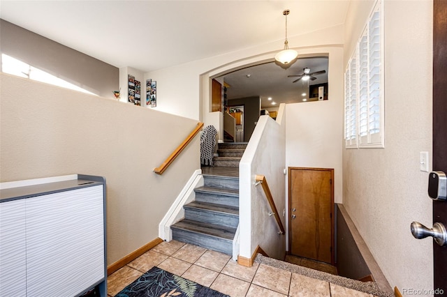 staircase featuring tile patterned floors and ceiling fan