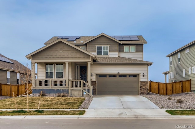craftsman-style house featuring covered porch, solar panels, fence, and concrete driveway