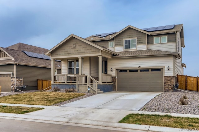 craftsman-style house with a porch, fence, concrete driveway, a garage, and solar panels