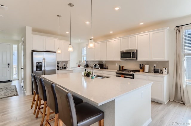 kitchen with a healthy amount of sunlight, stainless steel appliances, light wood-style flooring, and a sink