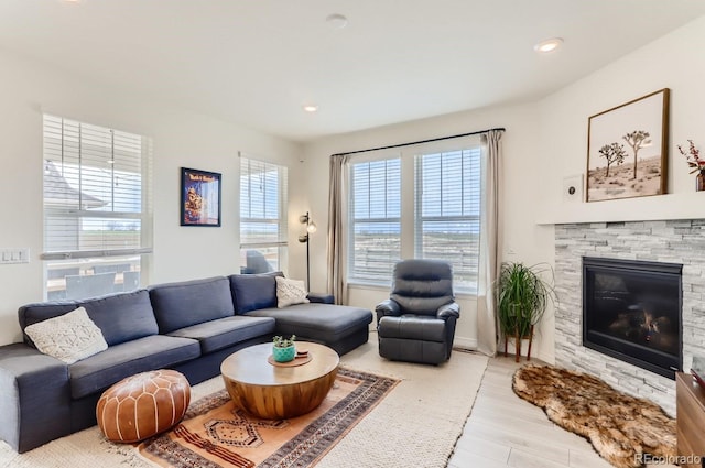 living area featuring baseboards, a stone fireplace, recessed lighting, and wood finished floors