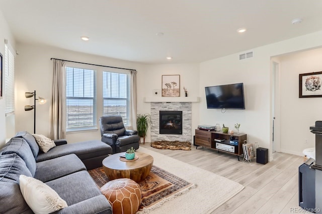 living room featuring light wood finished floors, visible vents, a fireplace, and recessed lighting