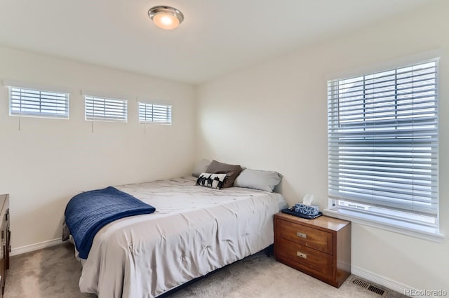 bedroom featuring baseboards, visible vents, and light colored carpet