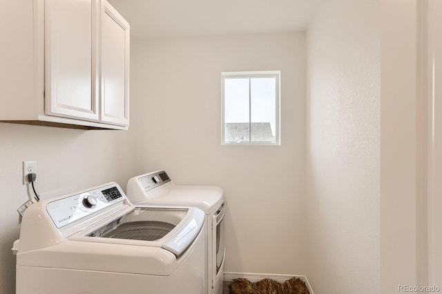 clothes washing area with washing machine and clothes dryer, baseboards, and cabinet space