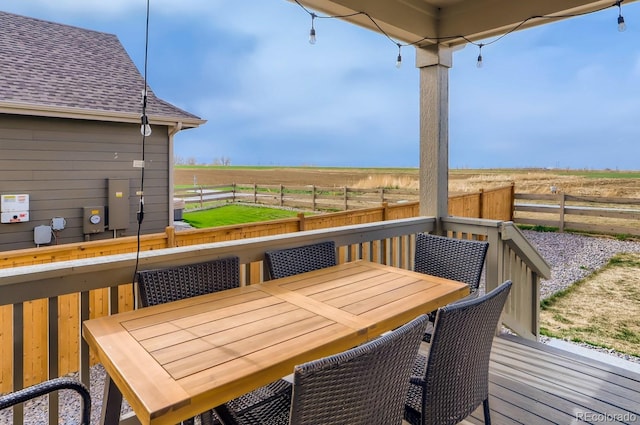 wooden deck with a rural view, outdoor dining area, and a fenced backyard