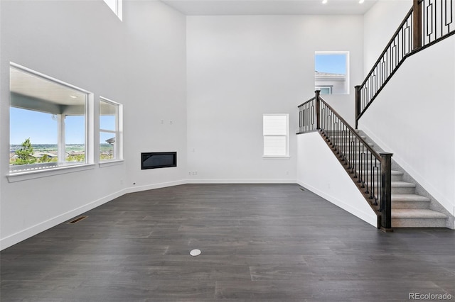 16565 Black Rose Cir, Parker, CO 80134 - unfurnished living room featuring plenty of natural light, a towering ceiling, stairway, dark wood finished floors, and baseboards