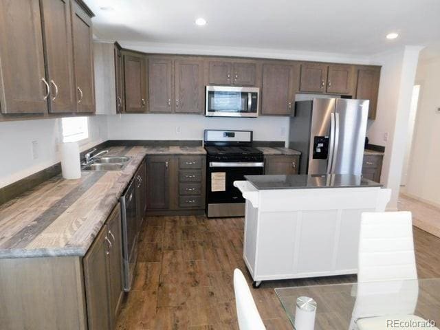 kitchen with dark brown cabinets, a center island, dark hardwood / wood-style flooring, stainless steel appliances, and sink