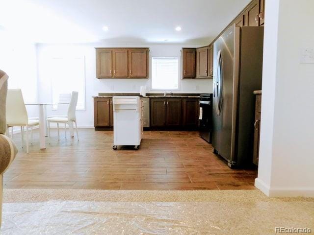 kitchen with stove, light hardwood / wood-style flooring, stainless steel refrigerator, and a center island