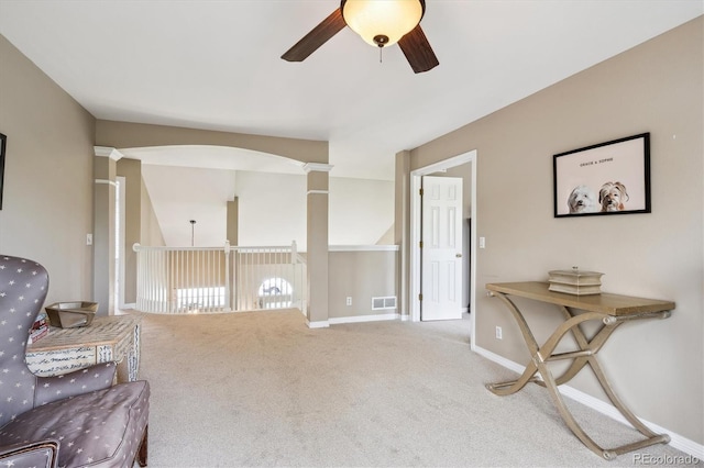 living area featuring carpet, ornate columns, visible vents, a ceiling fan, and baseboards