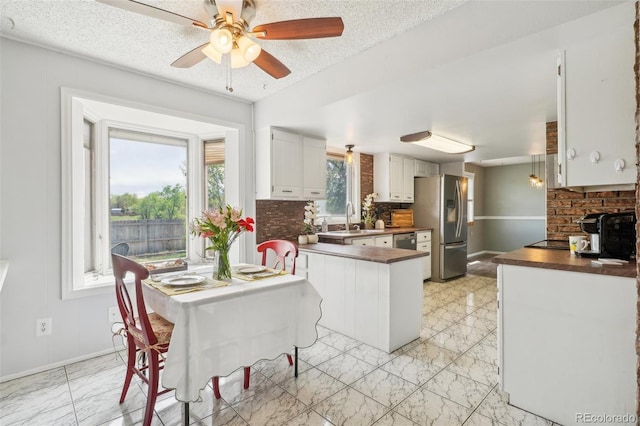 8732 W Arbor Ave, Littleton, CO 80123 - kitchen featuring stainless steel fridge, light marble finish floors, a peninsula, ceiling fan, and a textured ceiling
