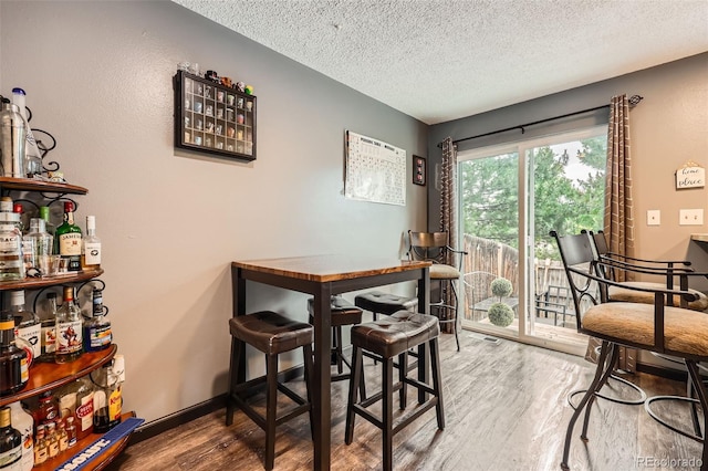 9672 W Chatfield Ave Unit C, Littleton, CO 80128 - dining space featuring a bar, a textured ceiling, and wood finished floors