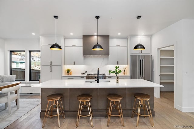 kitchen with stainless steel refrigerator, a center island with sink, a breakfast bar area, and sink