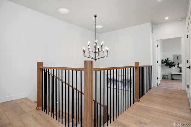 hall with light wood-type flooring and a notable chandelier