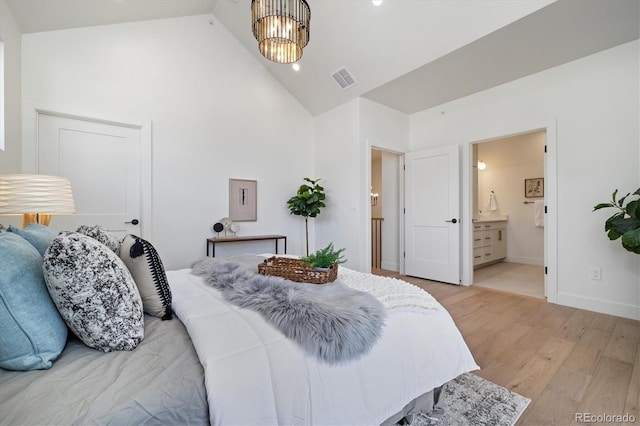 bedroom featuring high vaulted ceiling, ensuite bath, a chandelier, and light hardwood / wood-style flooring