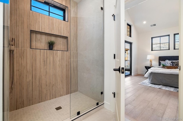 bathroom with lofted ceiling, walk in shower, hardwood / wood-style floors, and a healthy amount of sunlight