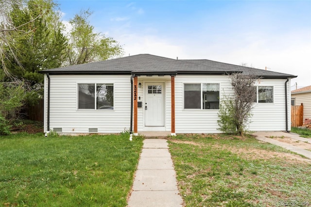 bungalow-style house featuring roof with shingles, fence, and a front lawn