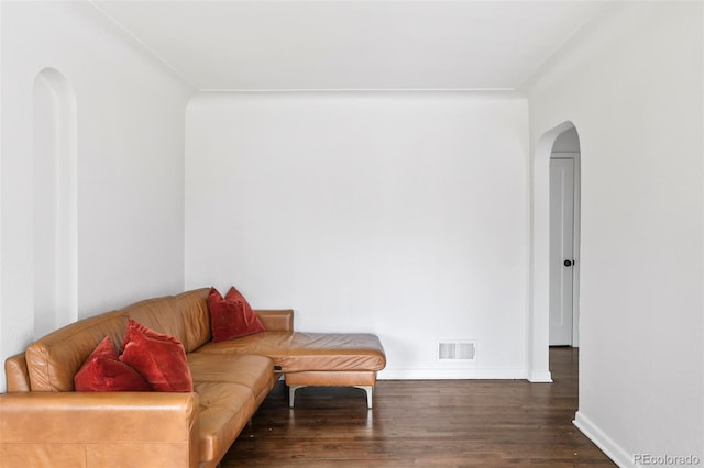 living area with arched walkways, baseboards, visible vents, and wood finished floors