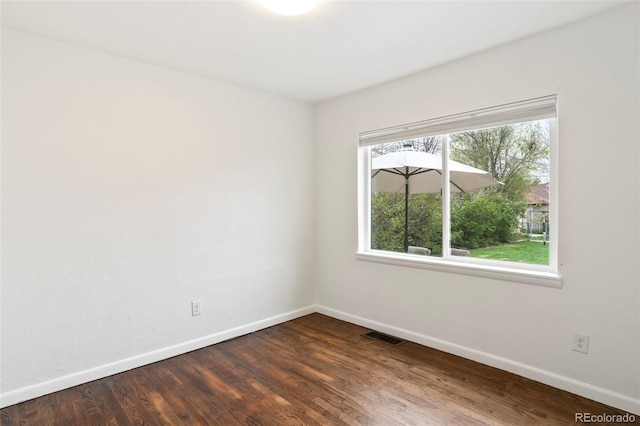 empty room with baseboards, dark wood finished floors, and visible vents
