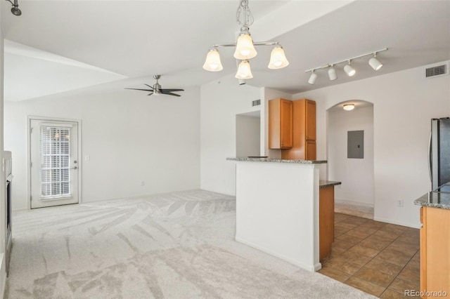 kitchen with visible vents, lofted ceiling, electric panel, dark stone countertops, and arched walkways