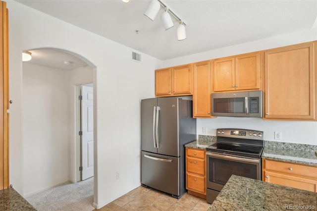 kitchen with light stone counters, visible vents, arched walkways, stainless steel appliances, and track lighting