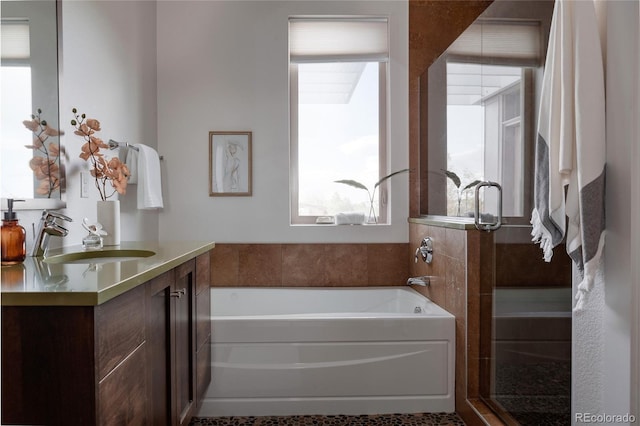 bathroom featuring a garden tub, a stall shower, and vanity