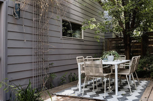 view of patio with fence, outdoor dining area, and a deck