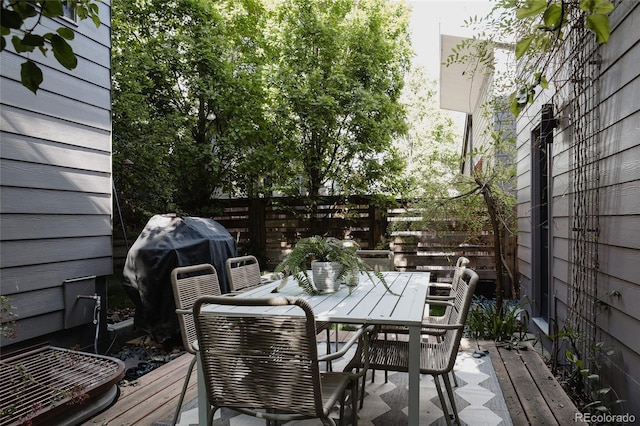 wooden terrace featuring fence, outdoor dining area, and grilling area