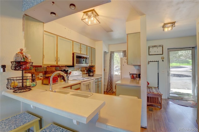 9771 W Cornell Pl, Lakewood, CO 80227 - kitchen with white electric stove, stainless steel microwave, a sink, light wood-style floors, and tasteful backsplash