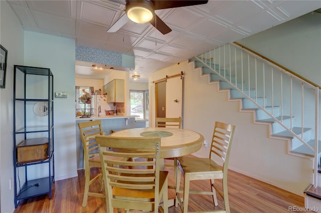 9771 W Cornell Pl, Lakewood, CO 80227 - dining area with a ceiling fan, a barn door, stairs, light wood-type flooring, and an ornate ceiling