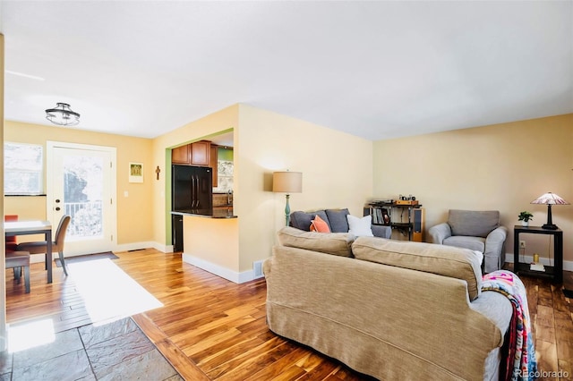 living room with visible vents, baseboards, and light wood finished floors