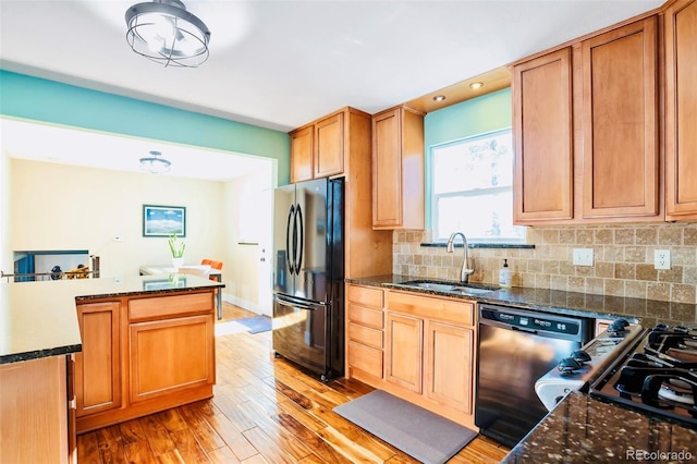 kitchen featuring light wood-type flooring, a sink, freestanding refrigerator, decorative backsplash, and dishwasher