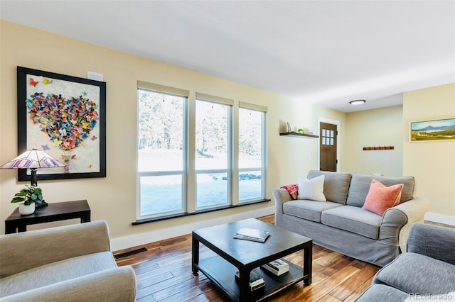 living area featuring visible vents, wood finished floors, and baseboards