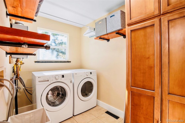 clothes washing area featuring light tile patterned floors, visible vents, baseboards, washing machine and clothes dryer, and cabinet space