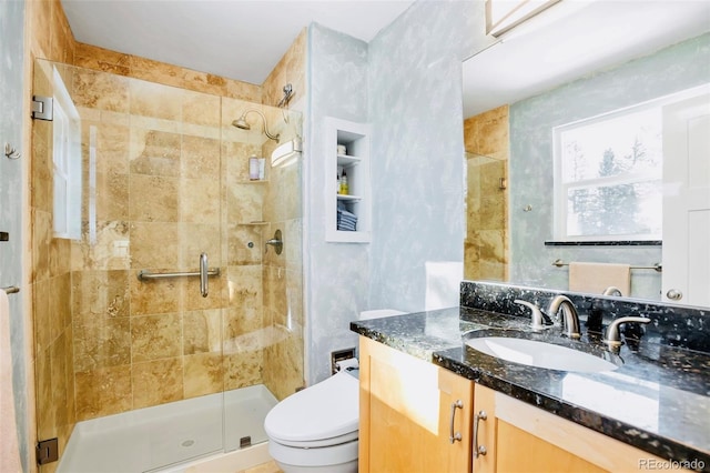 bathroom featuring a shower stall, toilet, and vanity