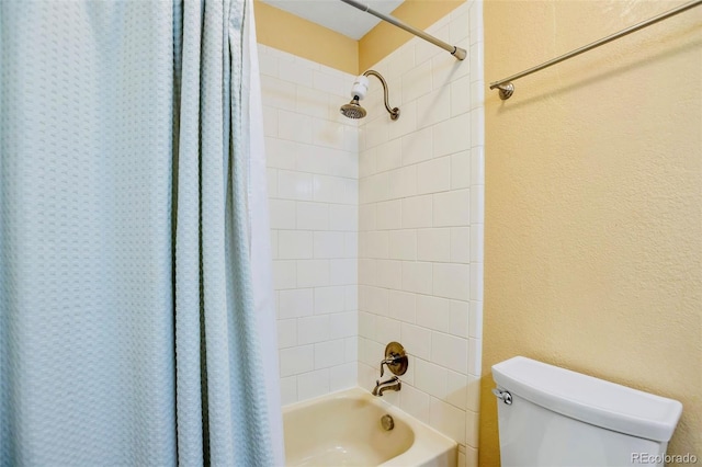 bathroom with shower / bath combination with curtain, toilet, and a textured wall