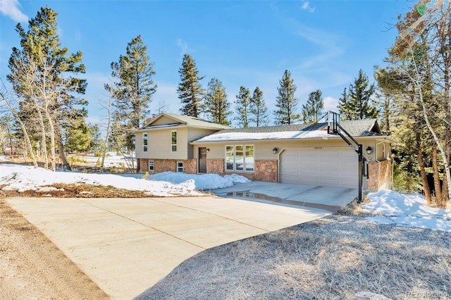 split level home with brick siding, a garage, and driveway