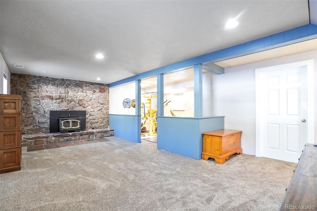 unfurnished living room featuring a wood stove, carpet flooring, and recessed lighting