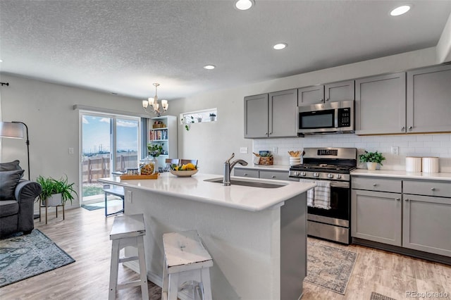 11051 Linley Way, Colorado Springs, CO 80908 - kitchen with stainless steel appliances, gray cabinets, a sink, a chandelier, and a breakfast bar area