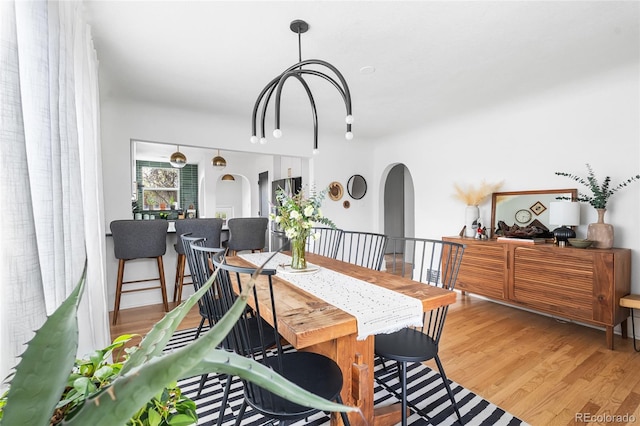 dining area with arched walkways and wood finished floors