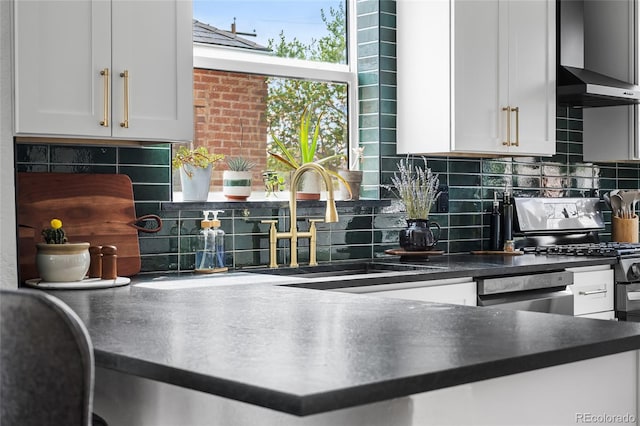 kitchen featuring backsplash, a sink, dark countertops, and white cabinetry
